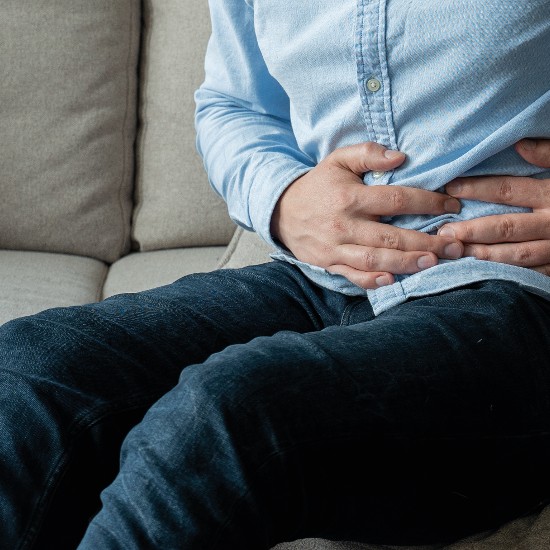 Mann hält sich den Bauch; Foto: Grustock/Shutterstock.com